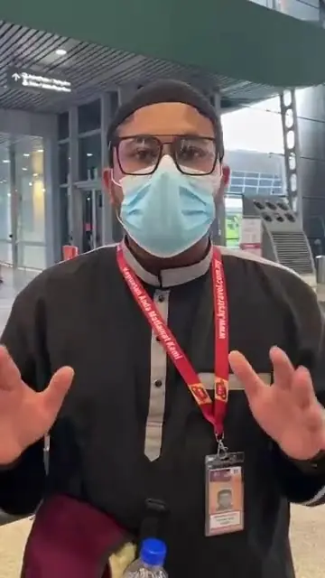 Jemaah lelaki berbaju melayu hitam bertali leher merah bercerita sambil menggerakkan tangan