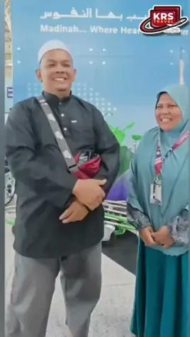 Sepasang jemaah suami isteri berdiri di hadapan papan tanda bertulis Madinah di ruang legar