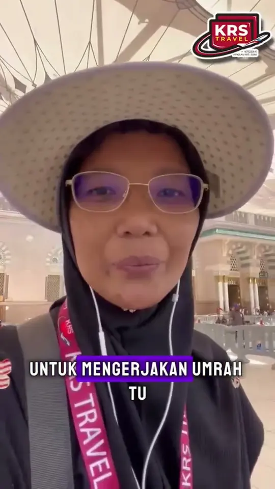 Jemaah wanita bertopi lebar dan bertali leher KRS Travel bercakap di ruang legar lapangan terbang