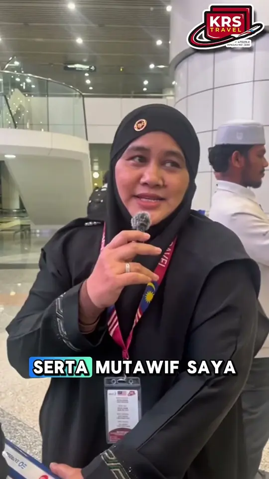 Jemaah wanita bercakap ke dalam mikrofon di lapangan terbang, memuji mutawwif KRS Travel