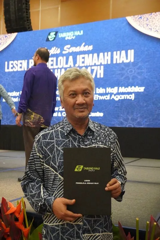 Wakil KRS Travel memegang fail Lesen Pengelola Jemaah Haji di Majlis Serahan Lesen 1447H