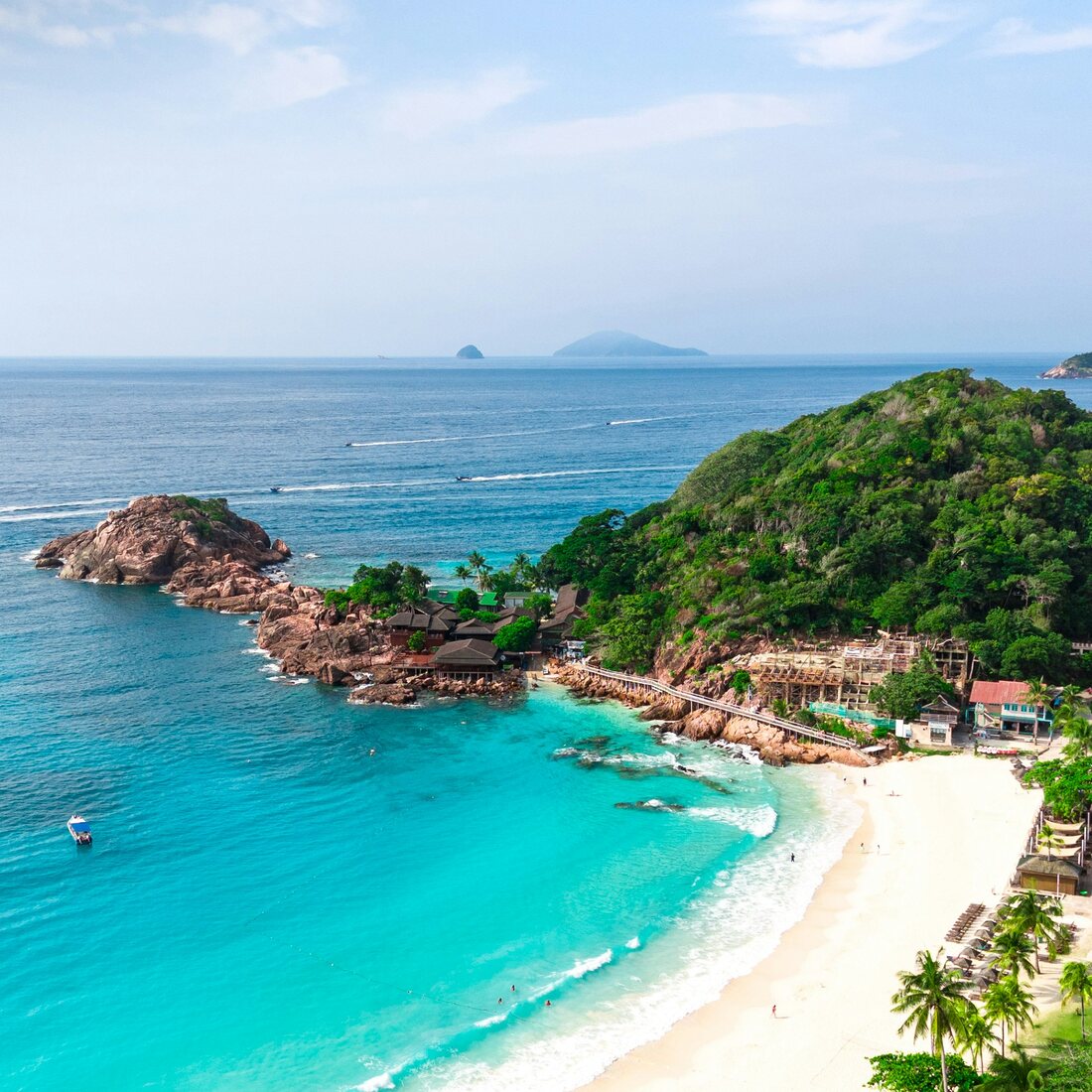 Pandangan udara teluk Pulau Redang — air pirus, pantai berpasir putih dan chalet resort berbumbung merah di tepi bukit berhutan, Terengganu — Pakej Pulau Redang KRS Travel