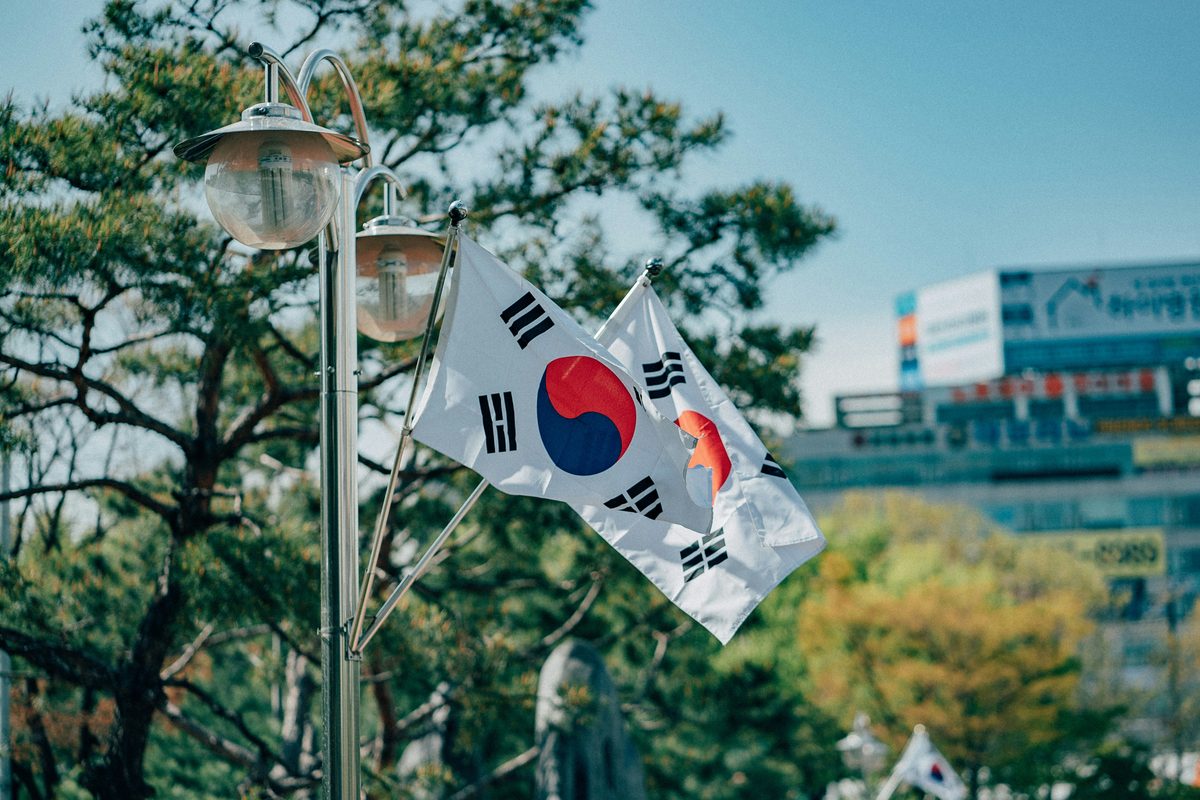 Bendera Korea Selatan berkibar di sebelah lampu jalan dengan latar bandar — Pakej Korea Selatan KRS Travel