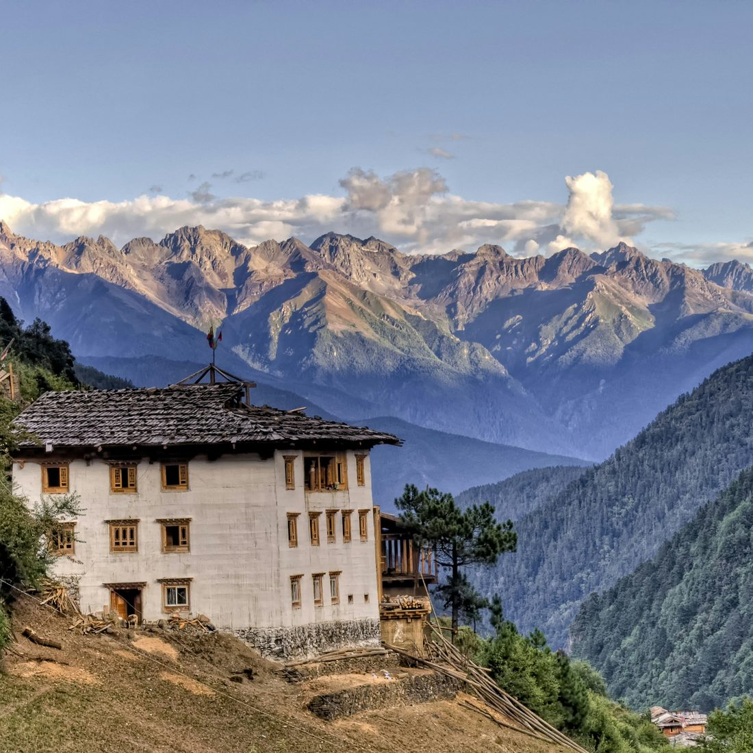 Rumah tradisional di lereng gunung dengan latar barisan puncak berbatu di pedalaman Yunnan, China — Pakej Yunnan KRS Travel