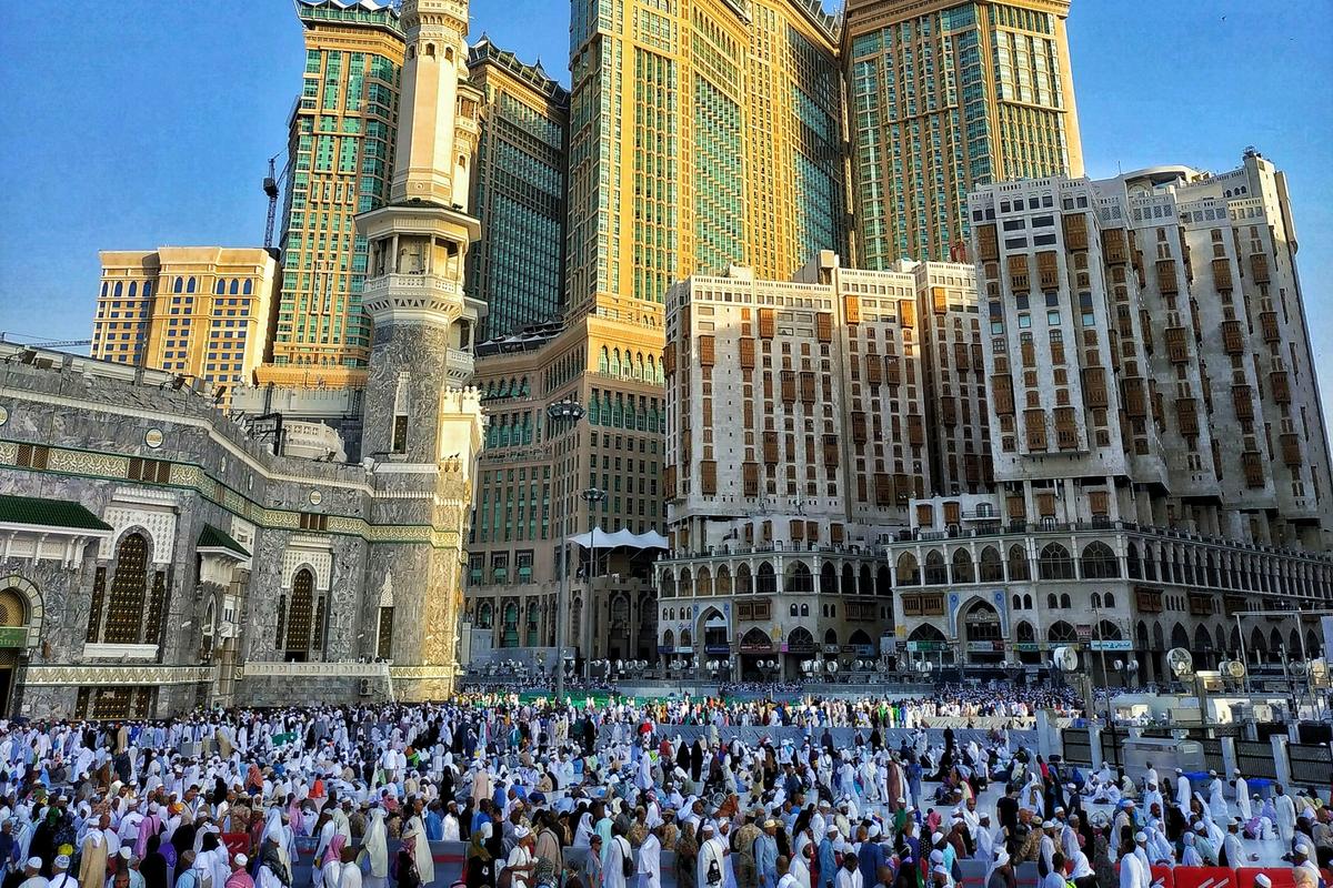 Jemaah umrah berihram di dataran Masjidil Haram dengan Menara Jam Diraja Makkah dan bangunan Abraj Al Bait di latar belakang